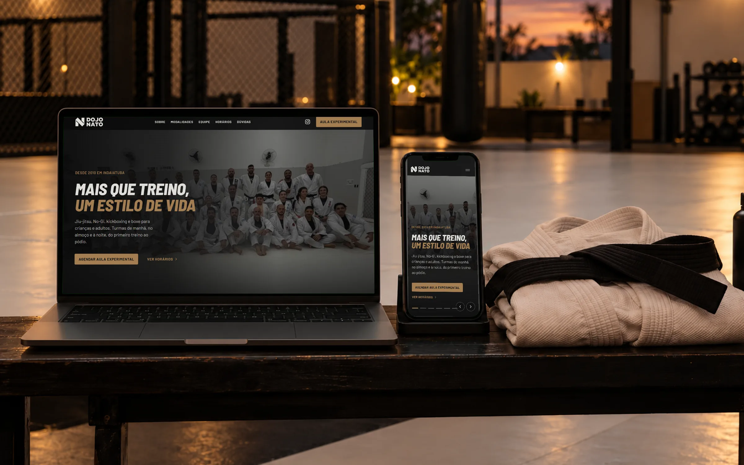 Site da Dojo Nato aberto num notebook, com o celular ao lado